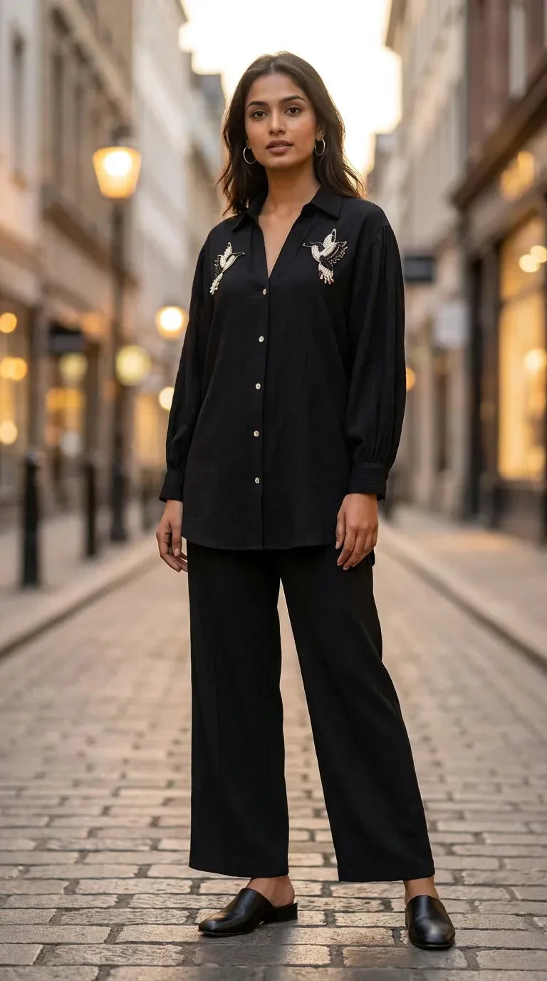 Woman wearing Karchobi black shirt co-ord set with bird motif, posing on a city street