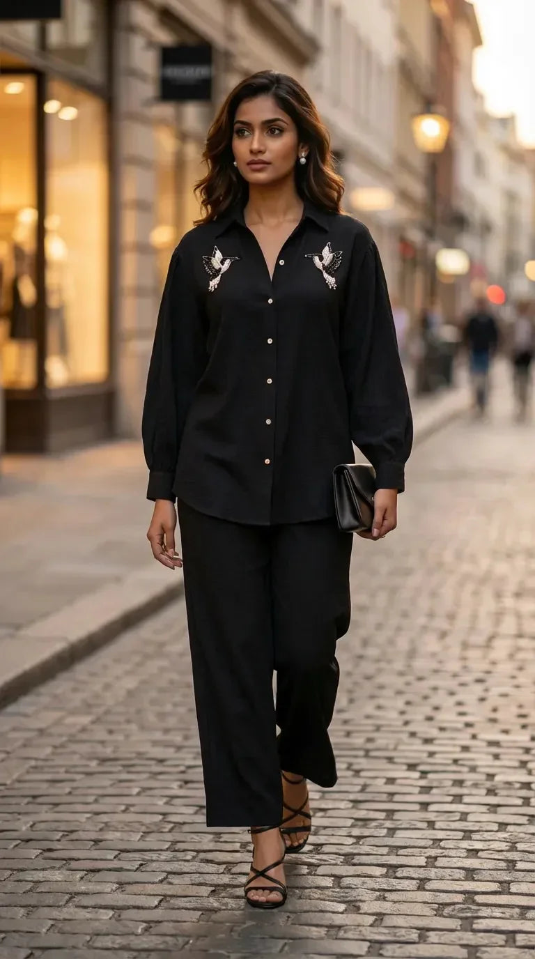 Woman wearing Karchobi black shirt co-ord set with bird motif, walking on city street