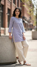 Woman wearing blue floral print short kurta and cream bottoms from Karchobi, standing outdoors.