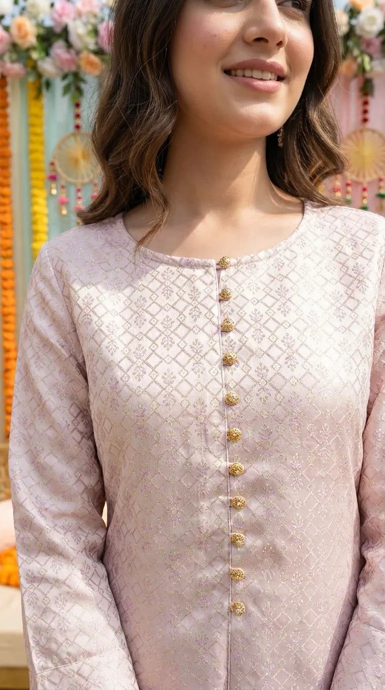 Woman wearing blush pink and gold jacquard silk kurta from Karchobi, floral decor behind