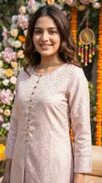 Woman in blush pink jacquard silk kurta set by Karchobi, floral backdrop, outdoor setting