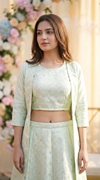 Woman in mint green jacquard silk crop top, long overlay jacket, and skirt by Karchobi