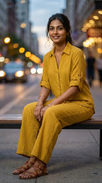 Woman in mustard yellow textured co-ord set from Karchobi sitting on a city bench at dusk