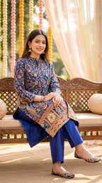 Woman wearing a navy blue gota paisley embroidered achkan kurta pant set from Karchobi, seated outdoors.