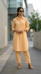 Woman in peach long shirt and pants co-ord set from Karchobi, modern outdoor setting