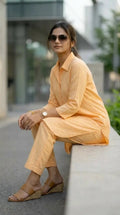 Woman wearing peach co-ord long shirt and pant set from Karchobi, seated outdoors