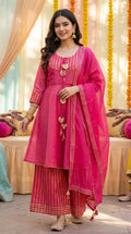 Woman in pink peplum sharara set with gold gotta lace from Karchobi, festive backdrop