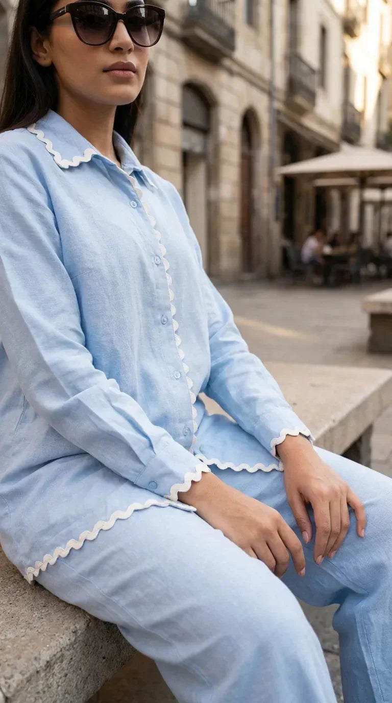 Woman wearing a powder blue scallop lace shirt co-ord set from Karchobi, seated outdoors.