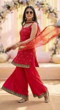 Woman in a sleeveless rani pink chinon kurta sharara set with floral embroidery, styled for a festive occasion, from Karchobi women's clothing collection.