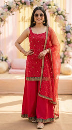 Woman in sleeveless rani pink floral embroidered kurta sharara set, gold trim dupatta, outdoor event