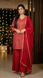 Woman wearing red and gold zari kurta crushed sharara set from Karchobi, festive background