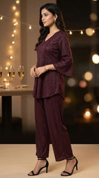 Woman in wine shimmer peplum box pleat co-ord set from Karchobi, festive evening setting